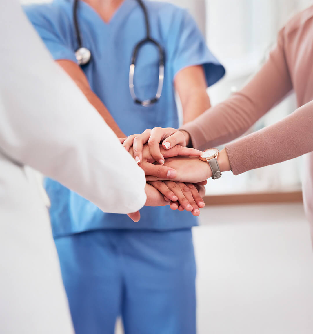 Équipe médicale unie posant leurs mains ensemble en signe de collaboration et d'engagement envers les soins aux patients